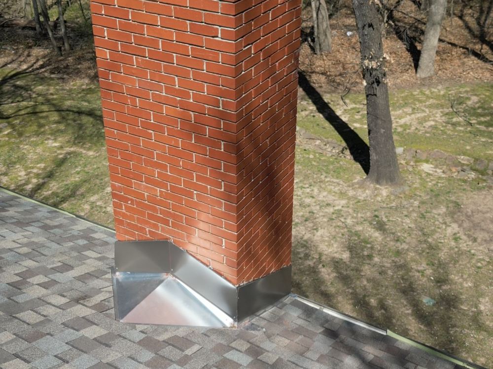 New step flashing installed by RainTech Roofing around a brick chimney