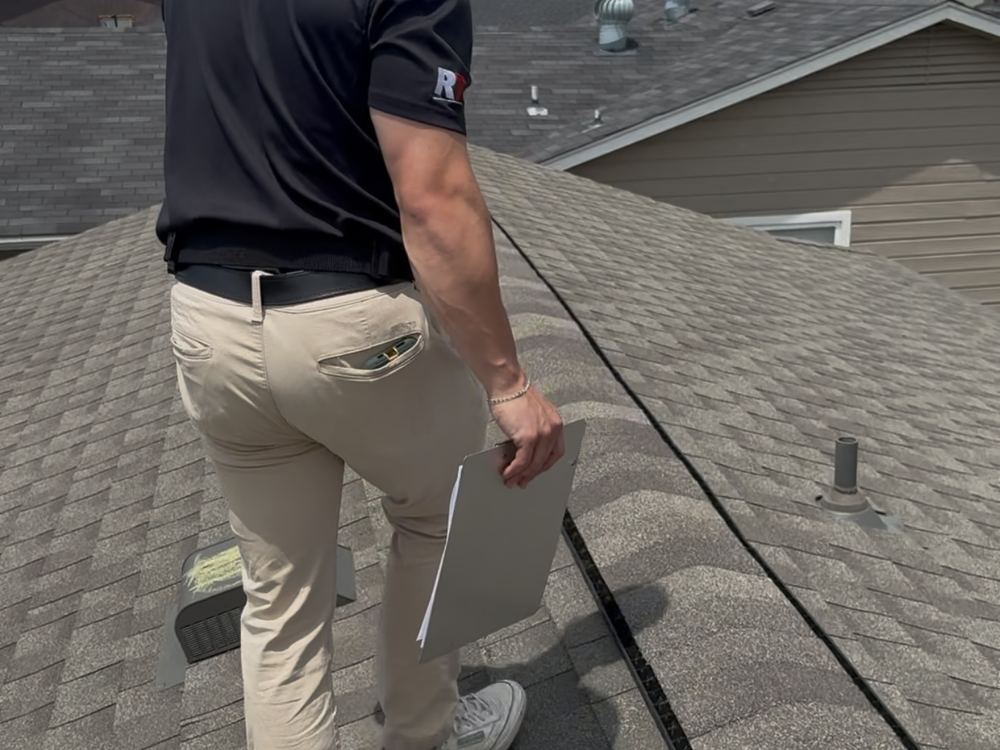 RainTech Roofing project manager walking a roof with a clipboard